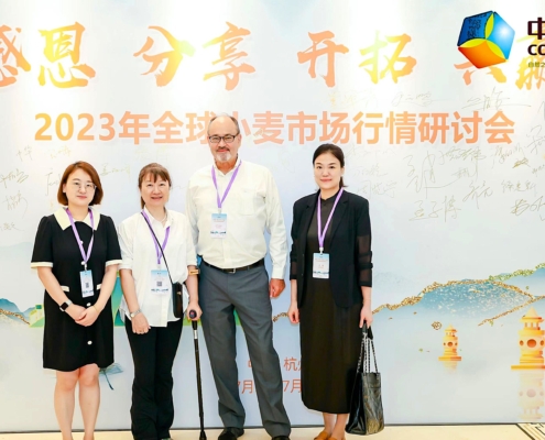 Photo of 4 people standing in front of a backdrop with Chinese characters and landscape drawing.