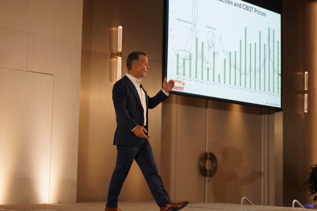 Photo of Joe Sowers in front of digital display of wheat supply and demand data at South and Southeast Asian Marketing Conference May 2025.