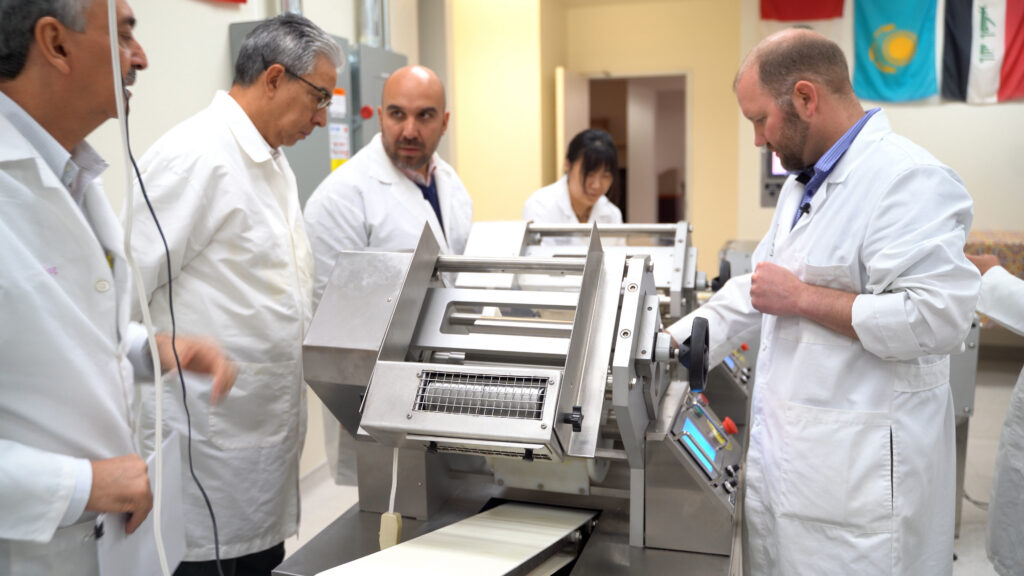 Saturno, center, helps a trade team from South America understand a process during a visit to the Wheat Marketing Center in Portland.
