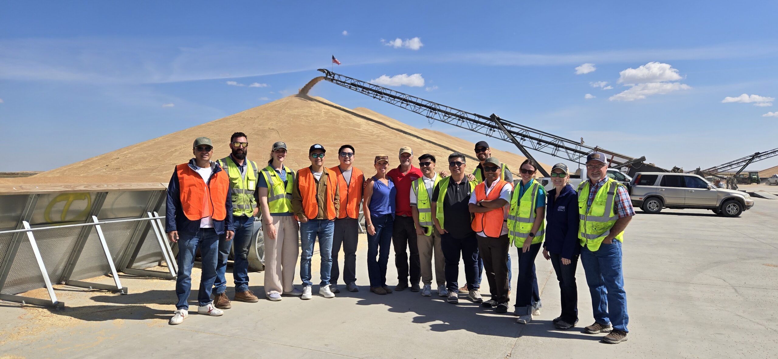 group of people in front of piles of grain