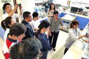 Seven Chinese baking managers, Ms. Shirley Lu, and Dr. Jayne Bock observing a technician at the Wheat Marketing Center conduct a falling number test on wheat flour.