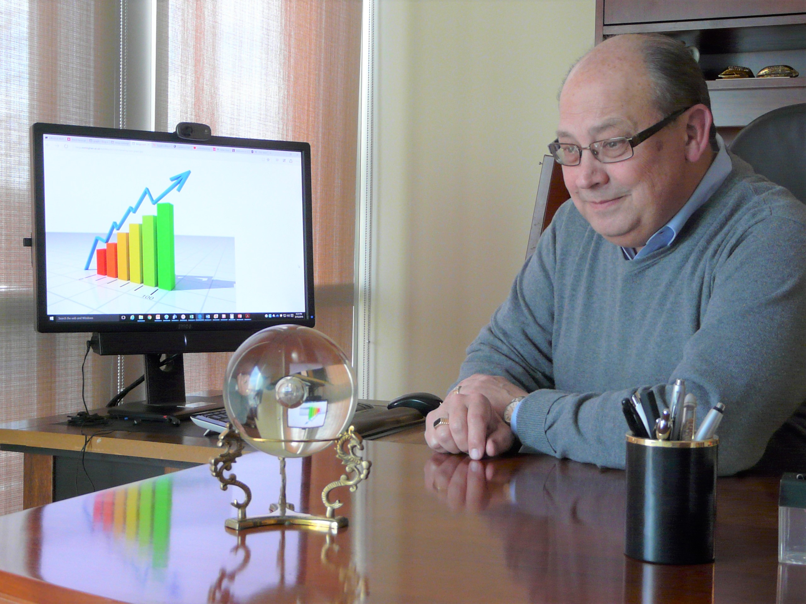 Photo shows Vince Peterson at his desk observing a crystal ball in front of a computer monitor.